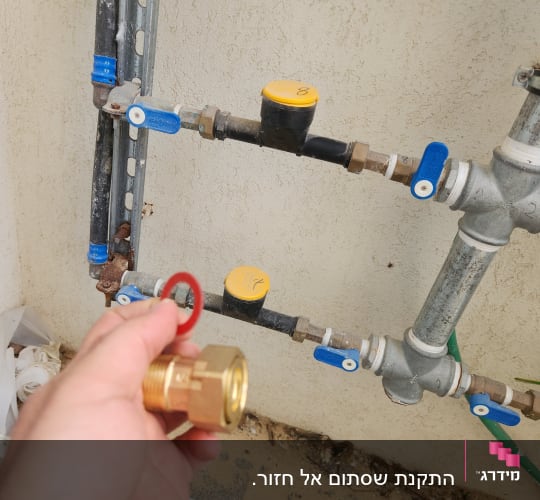 יד מחזיקה מחבר פליז ליד צינורות עם ברזים